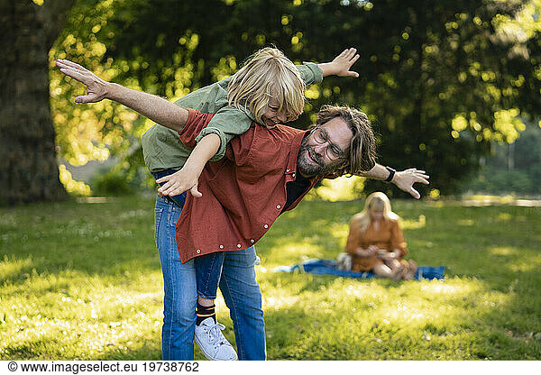 Smiling father having fun and playing with son in park