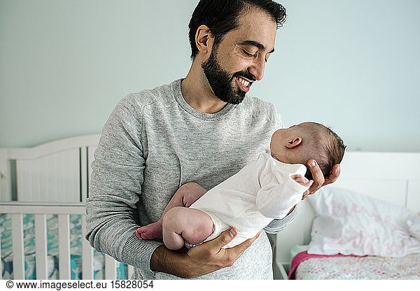 Smiling father with beard holds newborn baby