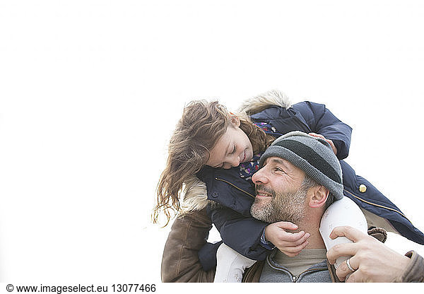 Smiling father with daughter against clear sky