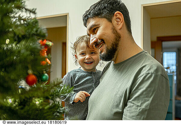 Smiling father with son looking at Christmas tree