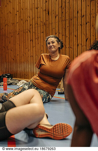 Smiling female athlete with disability sitting on floor at sports court