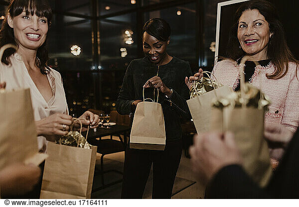 Smiling female colleagues with gift bags in office
