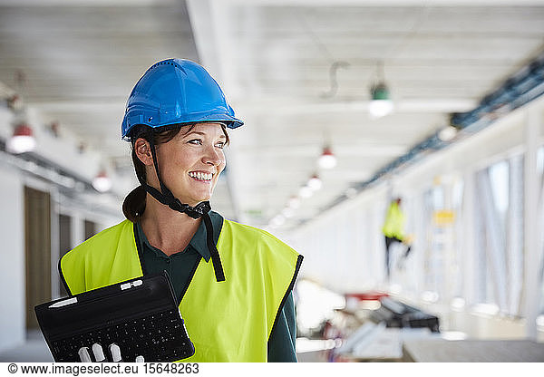 Smiling female construction manager in reflective clothing looking away