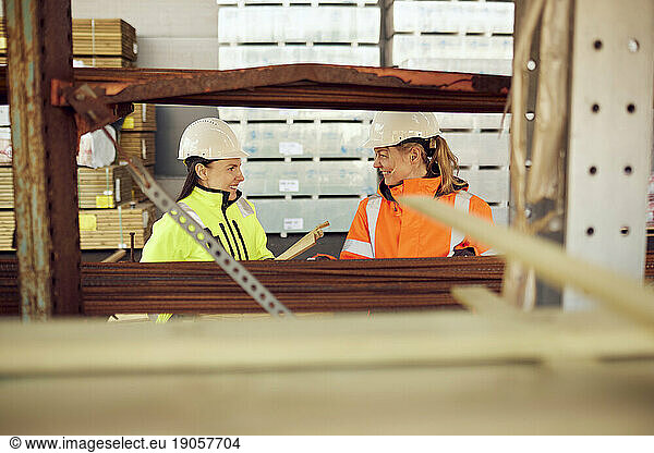 Smiling female coworkers discussing while working at distribution warehouse