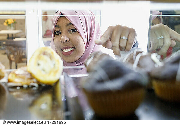 Smiling female customer pointing at pastry item in store