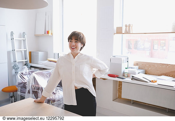 Smiling female design professional standing at desk in workshop