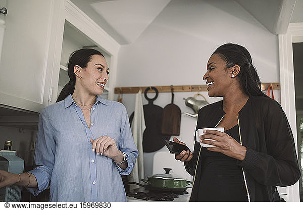 Smiling female design professionals discussing in kitchen at home office