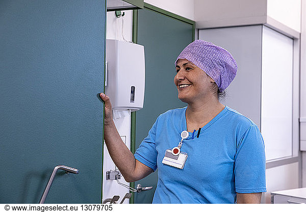 Smiling female doctor looking away while standing in hospital