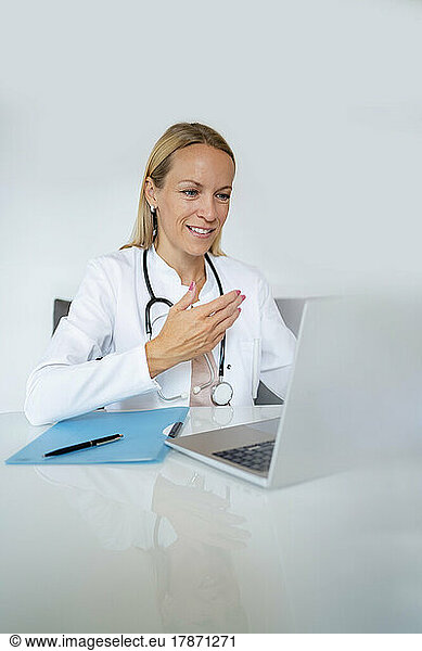Smiling female doctor using laptop at desk in medical practice