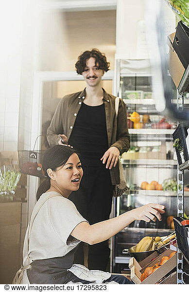 Smiling female employee pointing at rack in store