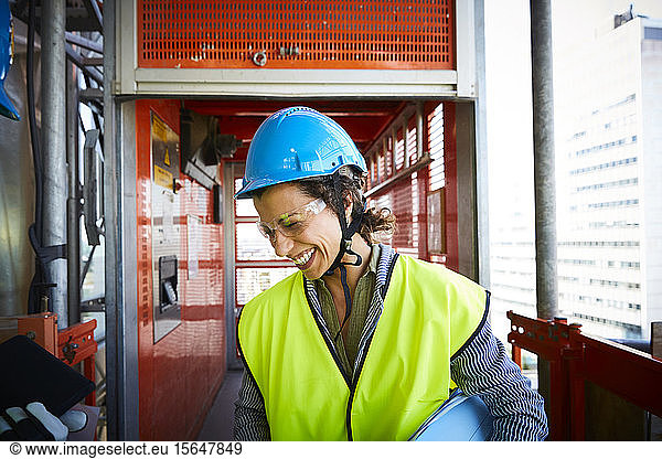 Smiling female engineer in reflective clothing at construction site