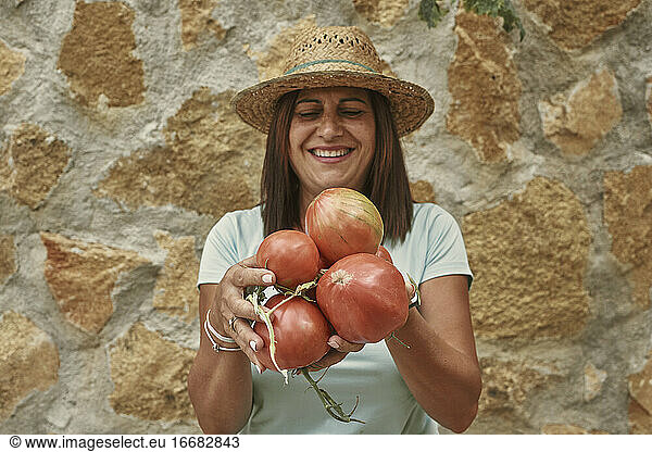 Smiling female farmer holding tomatoes while standing
