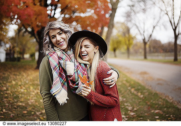 Smiling female fiends standing on field during autumn
