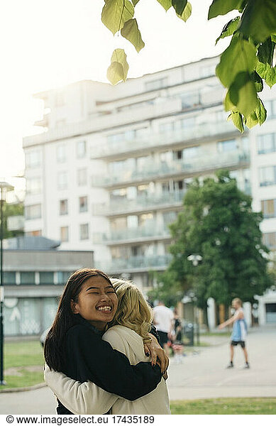 Smiling female friends embracing at park
