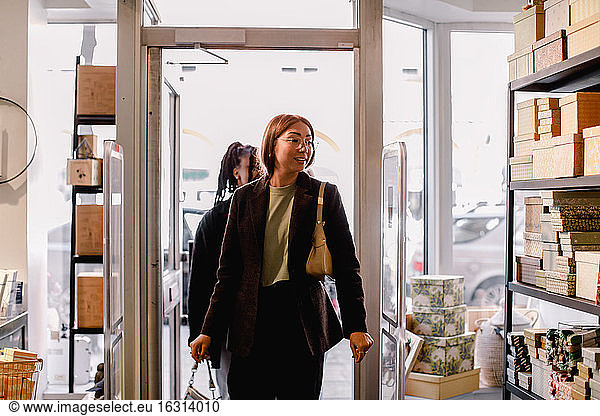 Smiling female friends entering retail store