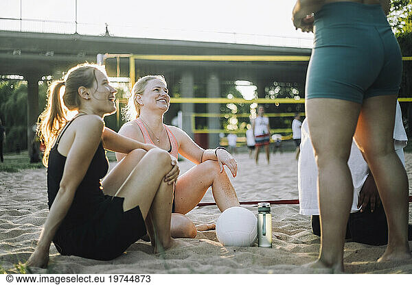 Smiling female friends talking to each other during volleyball match