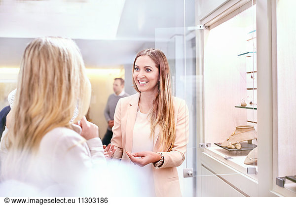 Smiling female jeweler helping customer in jewelry store