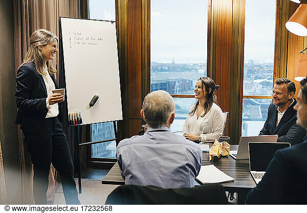 Smiling female lawyer giving presentation to colleagues in board room at office
