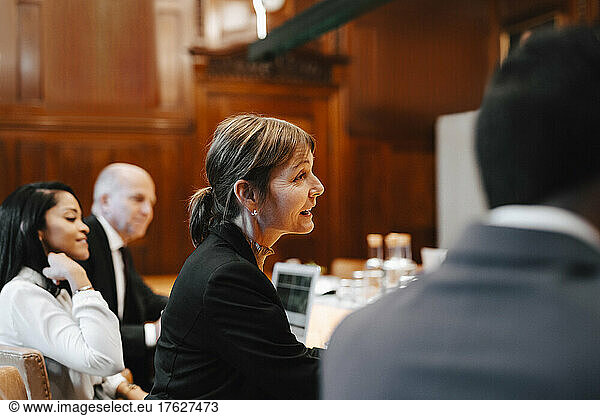 Smiling female lawyer in board room with colleagues during meeting