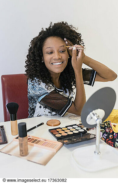 Smiling female make-up artist brushing eyebrows in studio