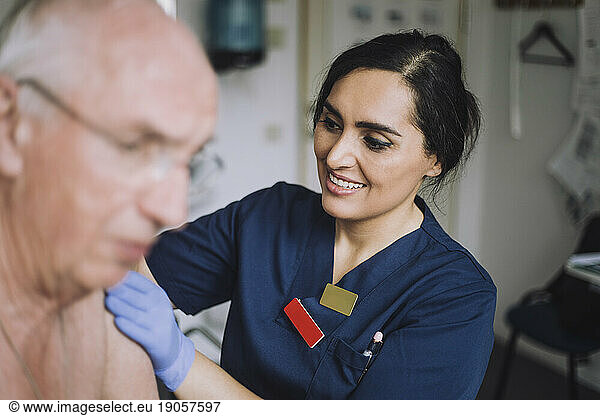 Smiling female nurse doing medical exam of senior patient at hospital