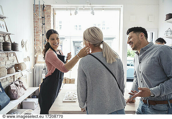Smiling female owner looking at woman's earring in design studio