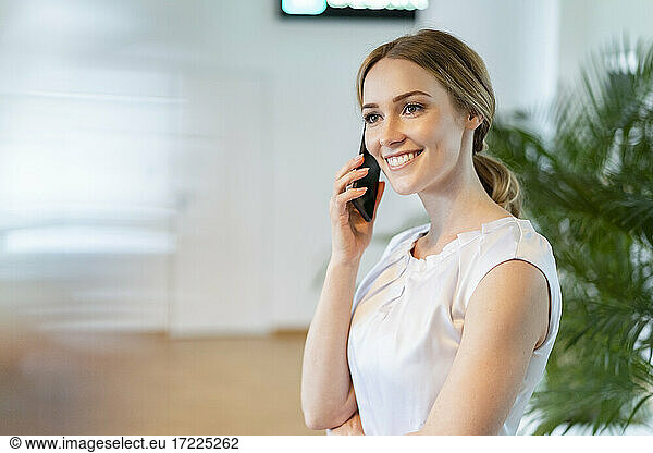 Smiling female professional talking on mobile phone in office