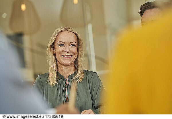 Smiling female professional with colleagues in meeting