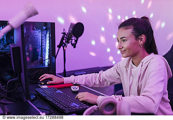Smiling female singer using computer in studio