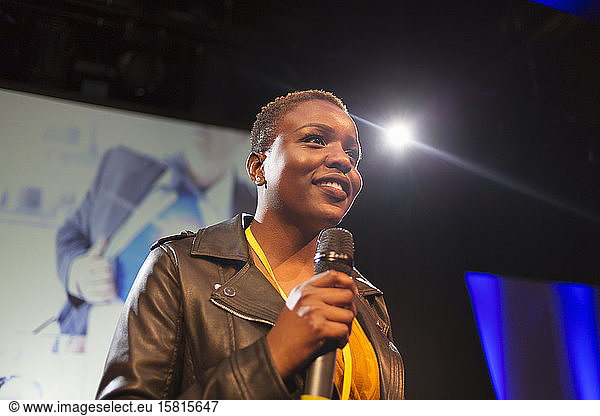 Smiling female speaker with microphone on stage