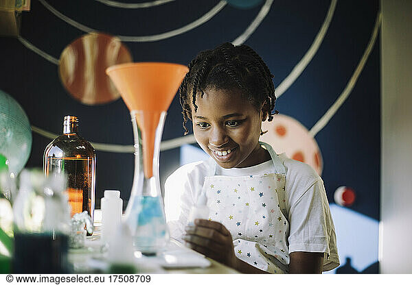 Smiling female student learning science project at home