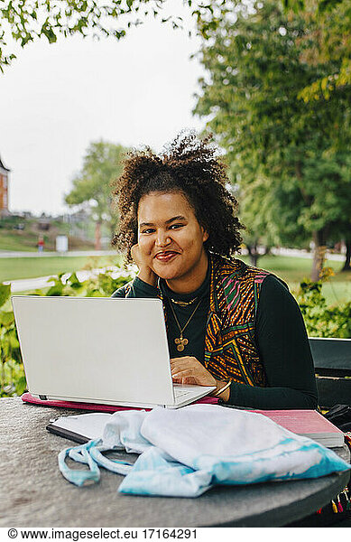Smiling female student with laptop in college campus