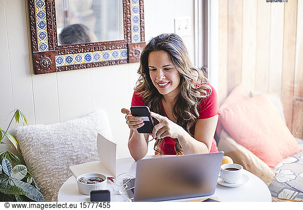 Smiling female using phone while sitting at table