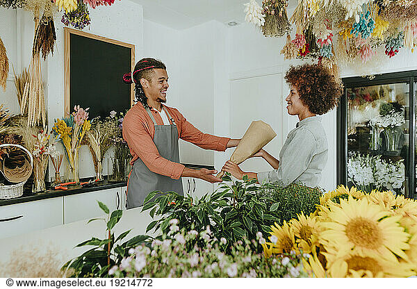 Smiling florist giving bouquet to customer at flower shop