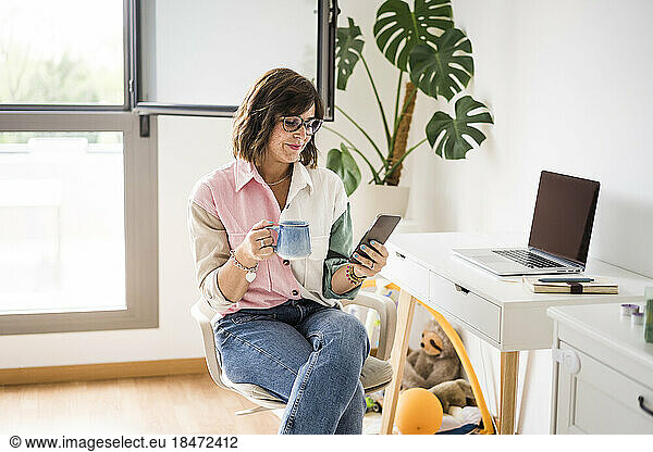 Smiling freelancer using smart phone at home