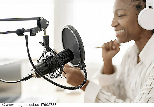 Smiling freelancer with microphone at home office