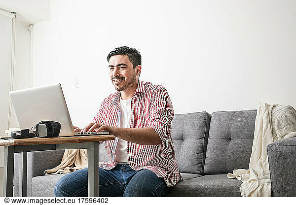 Smiling freelancer working on laptop at home