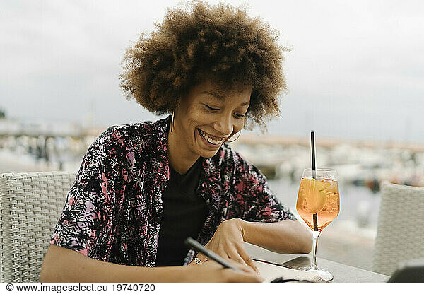 Smiling freelancer writing in diary at table