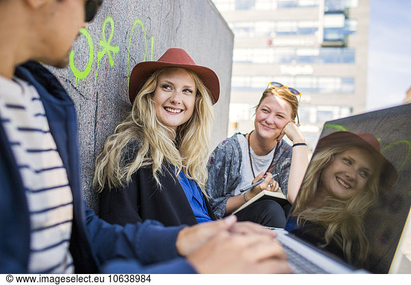 Smiling freelancers using laptop in city