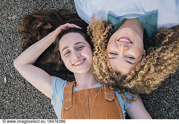 Smiling friends lying on road smiling at camera