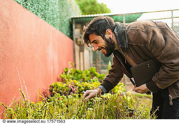 smiling gardener checking the condition and growth of plants