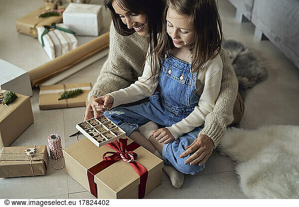 Smiling girl and mother with decoration box packing gift at home