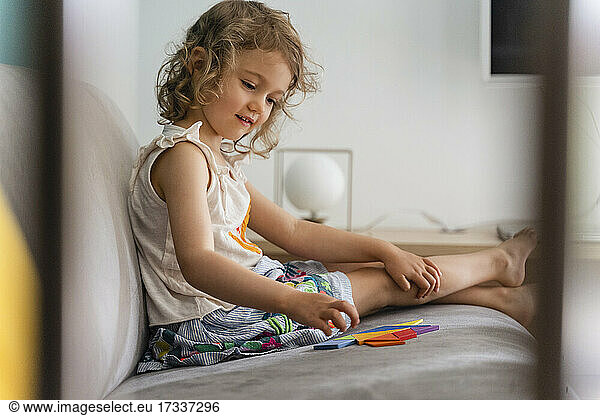 Smiling girl arranging puzzle while sitting at home
