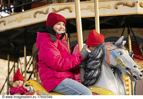 Smiling girl enjoying carousel ride at Christmas market