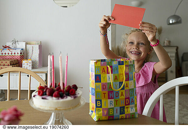 Smiling girl holding birthday card at home