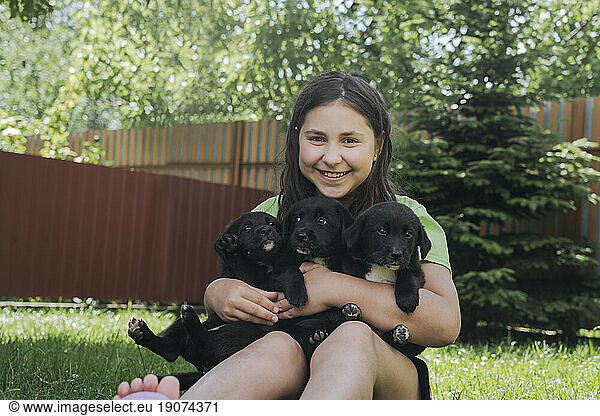Smiling girl holding puppies in back yard