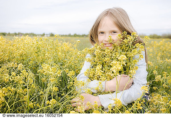 Smiling girl hugging rape flowers