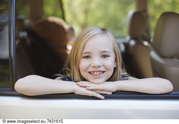 Smiling girl leaning out car window