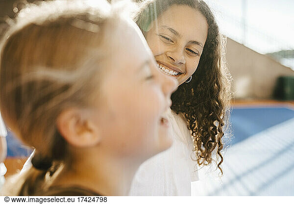 Smiling girl looking at female friend at sports court