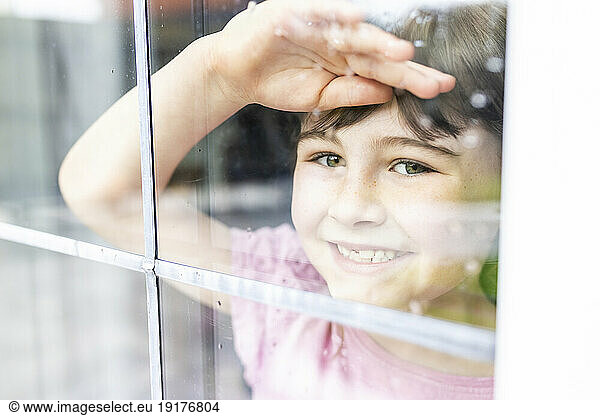 Smiling girl looking through window